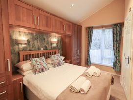 A bedroom with a bed and cabinets at Kingfisher Lodge Grasmere 33, White Cross Bay near Windermere