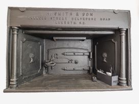 A fireplace with a metal door and remote control at The Old Bakery in Banbury
