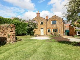 An outdoor view of a house with a garden and trees at The Old Bakery in Banbury