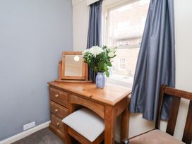A bedroom with a desk and flowers at Stowaway Cottage in Whitby