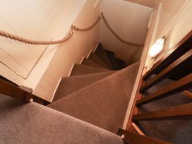A staircase with carpeted steps and a handrail at Stowaway Cottage Whitby