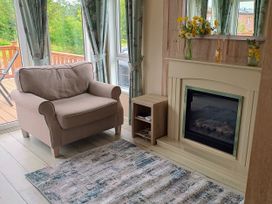 A living room with an armchair and fireplace at Fern Lodge in Stowmarket