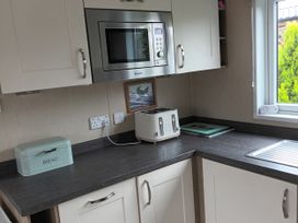 A kitchen with a microwave, toaster, and bread bin at Fern Lodge in Stowmarket