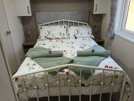 A bed with floral sheets and towels in a bedroom at Fern Lodge Stowmarket