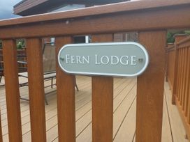 A name sign attached to a wooden railing at Fern Lodge in Stowmarket
