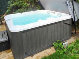 A hot tub on a patio in the garden at Fern Lodge in Stowmarket