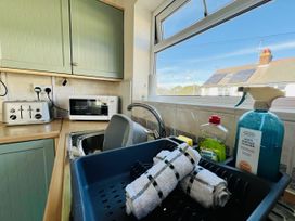 A kitchen with a sink, microwave, and cleaning supplies at 11 Langer Road, Felixstowe