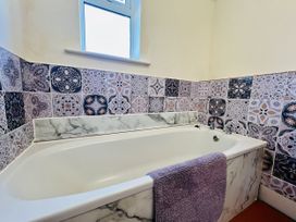 A bathtub with a towel and patterned tiles at 11 Langer Road in Felixstowe