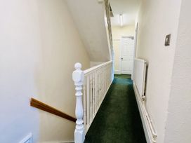 A hallway with a stair railing and door at 11 Langer Road Felixstowe