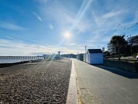 A beach path with beach huts and a pier at 11 Langer Road Felixstowe