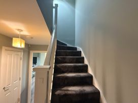 A staircase with a light fixture and door at 14 Becket Close Woodford Green