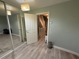 A hallway with a mirror and a door to stairs at 14 Becket Close in Woodford Green