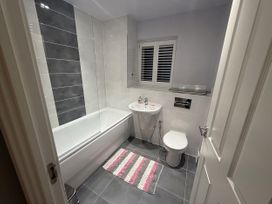 A bathroom with a bath tub toilet and sink at 14 Becket Close Woodford Green