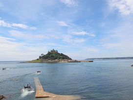 A view of an island with a castle and boats in the water at Praa Waves in Penzance
