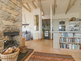 A living room with a stone fireplace and kitchen area at Harbour Lights in Penzance