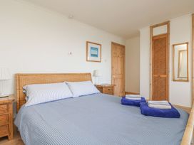 A bedroom with a bed, nightstand, and door at Harbour Lights in Penzance