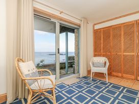 A living room with rattan and white chairs and a sliding door at Harbour Lights in Penzance