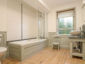 A bathroom with a bathtub, toilet, sink, and a chair at Harbour Lights in Penzance