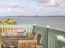 An outdoor deck with a table and chairs and a barbecue at Harbour Lights in Penzance