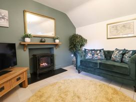 A living room with a fireplace and television at The Talkhouse Cottage in Caersws