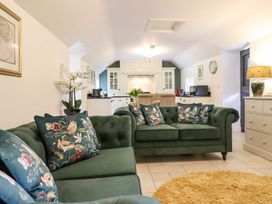 A living room with a green sofa and kitchen in view at The Talkhouse Cottage Caersws