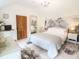 A bedroom with a bed, dresser, and mirror at The Talkhouse Cottage in Caersws