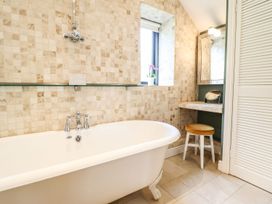 A bathroom with a bathtub and mirror at The Talkhouse Cottage in Caersws