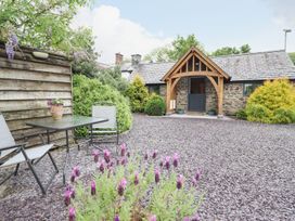 A garden with a table, chairs and flowers at The Talkhouse Cottage in Caersws