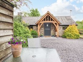 An outdoor view of a cottage with a gravel path and flowers at The Talkhouse Cottage in Caersws