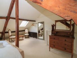 A bedroom with a dresser and mirror at Waterloo Mill Cottage in Wotton-Under-Edge