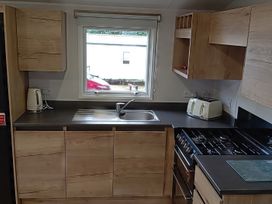 A kitchen with cabinets, a sink, stove, kettle, and toaster at Caravan Thorness Bay Holiday Park Thorness Lane