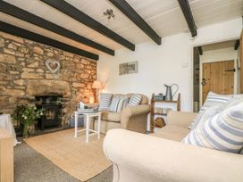 A living room with a stone wall and furniture at Driftwood Cottage in Helston