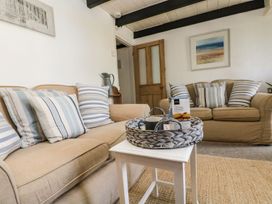 A living room with a sofa, table, and decorative items at Driftwood Cottage in Helston