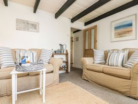 A living room with sofas and a table at Driftwood Cottage in Helston