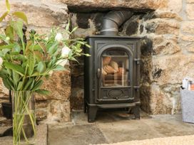 A wood stove with a flower vase in a living room at Driftwood Cottage Helston