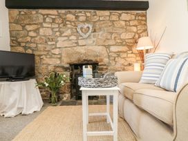 A living room with a stone wall and sofa at Driftwood Cottage in Helston