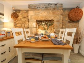 A dining room with a stone wall and table set for breakfast at Driftwood Cottage Helston