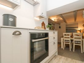 A kitchen with an oven and dining area at Driftwood Cottage in Helston