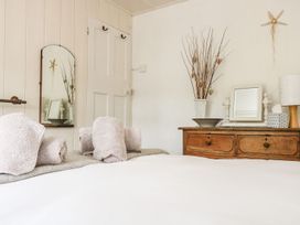 A bedroom with towels on the bed and a dresser at Driftwood Cottage in Helston