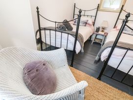 A bedroom with twin beds and a chair at Driftwood Cottage in Helston