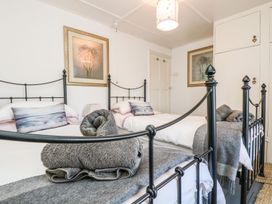 A bedroom with two beds and paintings on the wall at Driftwood Cottage Helston