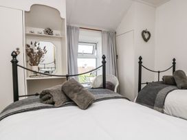 A bedroom with two beds and a window at Driftwood Cottage in Helston