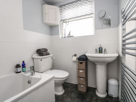 A bathroom with a bath tub, sink, and toilet at Driftwood Cottage in Helston