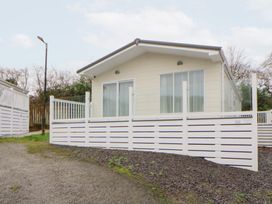 A cabin with white fencing and a gravel pathway at Beechwood Lodge in 