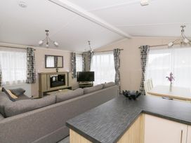 A living room with a sofa, television, and dining table at Beechwood Lodge