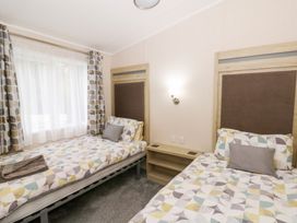 A bedroom with two beds and a shelf at Beechwood Lodge 
