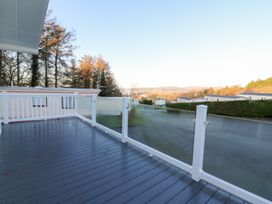 A deck with glass railing overlooking the landscape at Beechwood Lodge 
