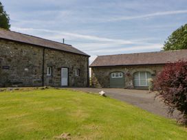 A stone building with a garage and landscaped garden at Shearers in Llandysul