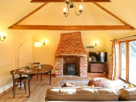 A living room with a fireplace and dining area at The Old Cow Shed