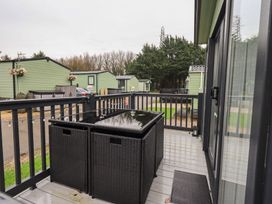 A deck with outdoor table and green caravans in view at Caravan